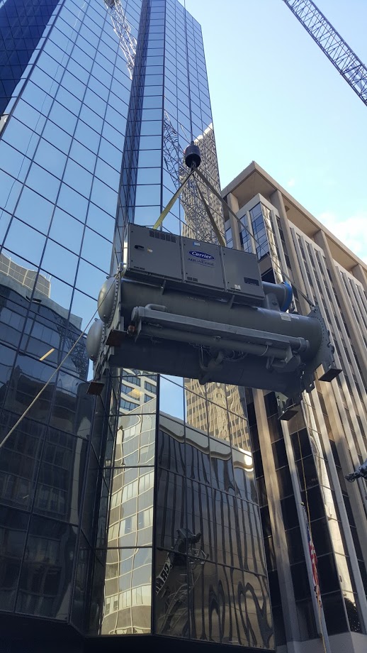 Crane lifting HVAC equipment to the roof of an office tower